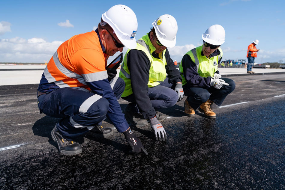 Workers inspecting the new layer of runway pavement